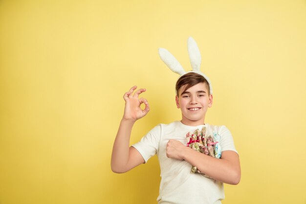 Ragazzo come un coniglietto di Pasqua sulla parete gialla dello studio