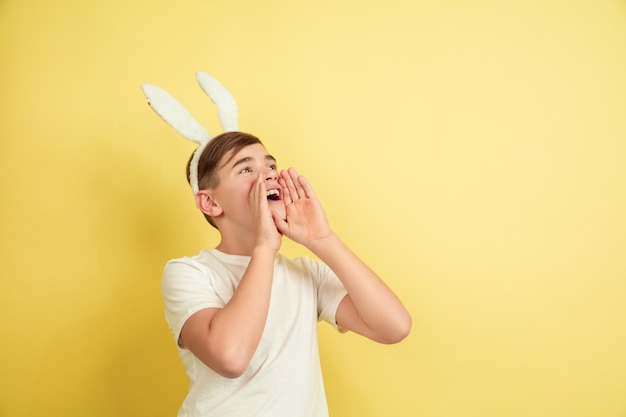 Ragazzo come un coniglietto di Pasqua sulla parete gialla dello studio