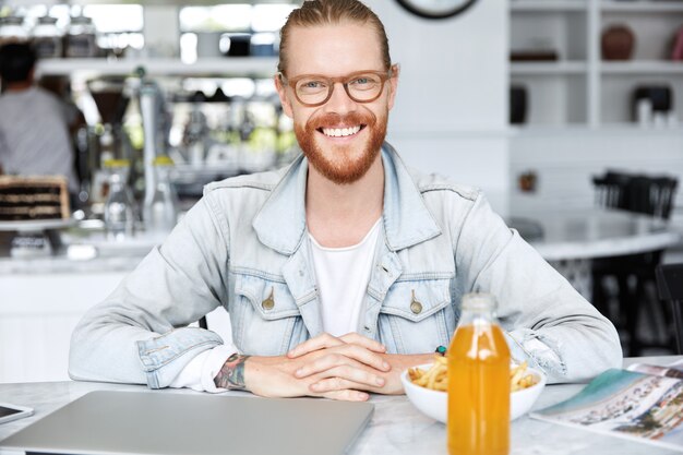 Ragazzo con i capelli lunghi, vestito con una giacca di jeans alla moda nella caffetteria