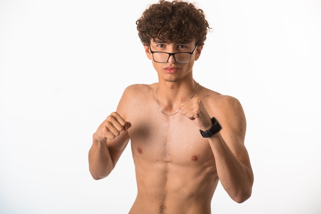 Ragazzo con i capelli ricci in vetri ottici che perfora con i pugni.