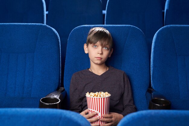 Ragazzo con la faccia di poker guardando film noioso nel cinema