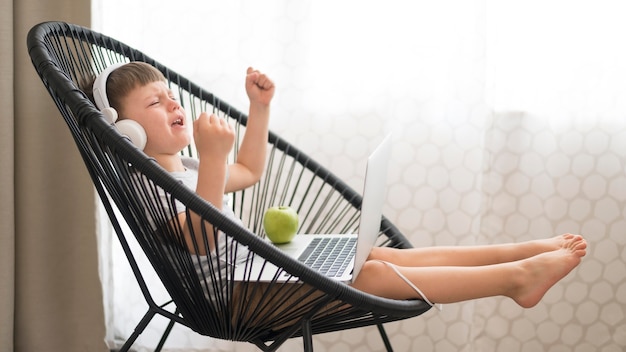 Ragazzo con le cuffie e computer portatile sulla sedia