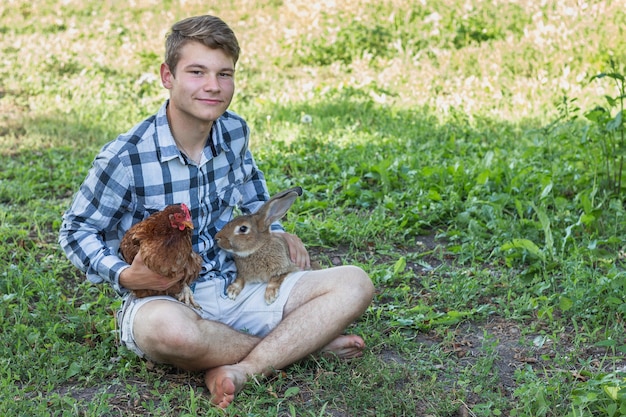 Ragazzo con le gambe incrociate con conigli e pollo