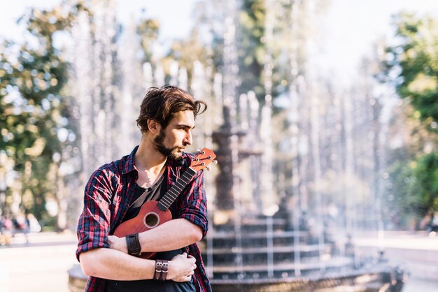 Ragazzo con ukelele di fronte a una fontana