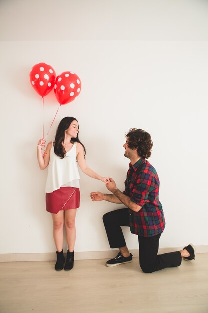 Ragazzo con un ginocchio sul pavimento e tenendo la mano della sua ragazza