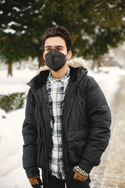 Ragazzo con una maschera. Indiano in vestiti pesanti. Uomo sulla strada in inverno.