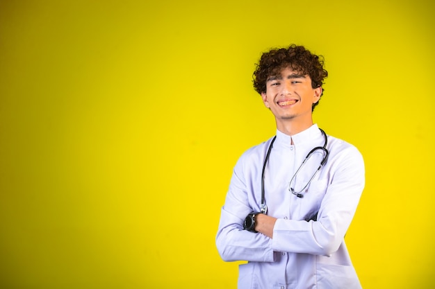 Ragazzo dei capelli ricci in uniforme medica bianca con lo stetoscopio.