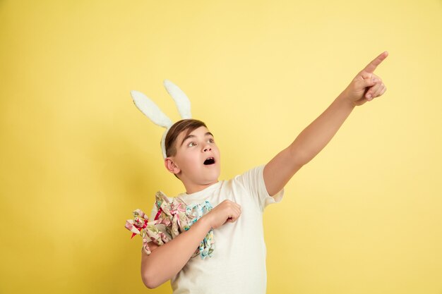 Ragazzo del coniglietto di pasqua con emozioni luminose sulla parete gialla dello studio