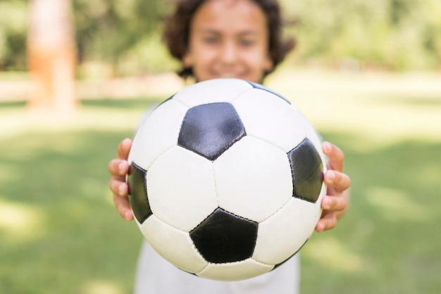 Ragazzo del primo piano che gioca con la palla di calcio