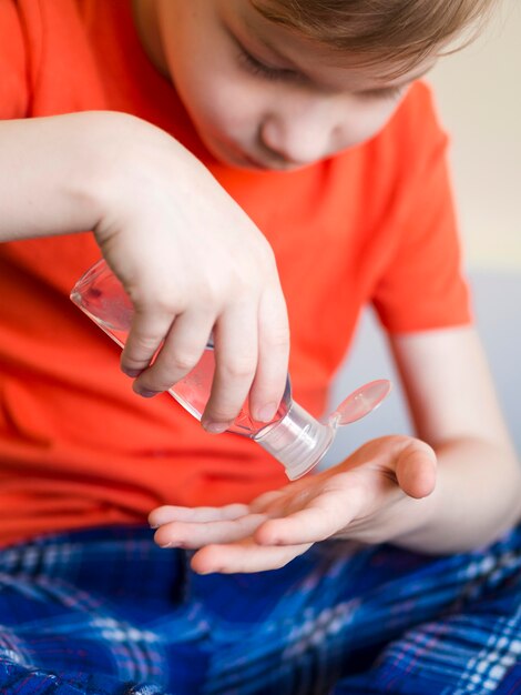 Ragazzo del primo piano che usando disinfettante per le mani