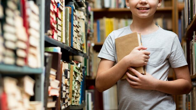 Ragazzo del primo piano fra gli scaffali per libri