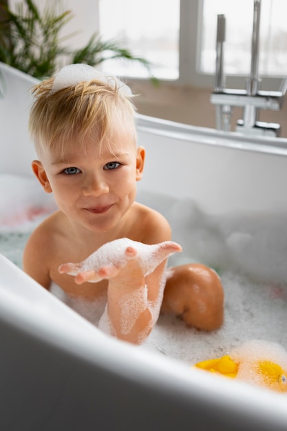 Ragazzo del tiro medio che gioca nella vasca da bagno