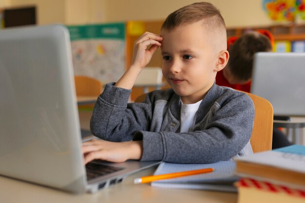 Ragazzo del tiro medio che impara con il computer portatile