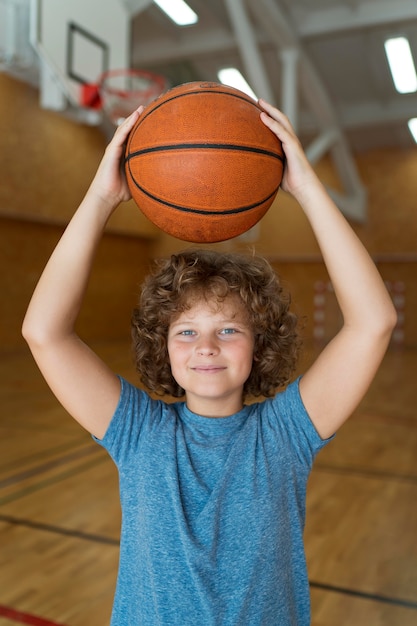 Ragazzo del tiro medio che tiene palla da basket