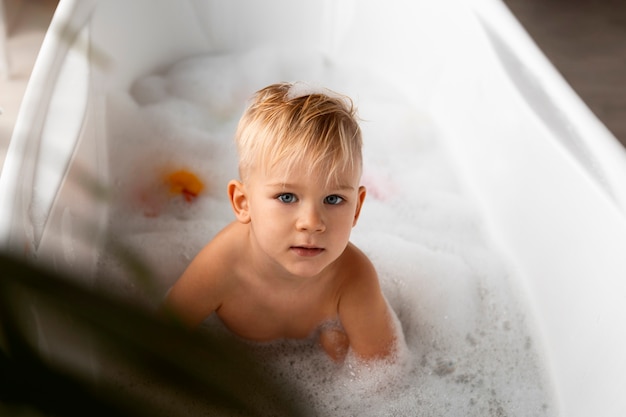 Ragazzo dell'angolo alto che gioca nella vasca da bagno