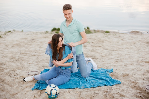 Ragazzo della foto a figura intera che mette una giacca al suo amico