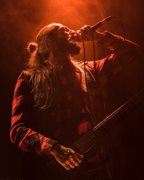 Ragazzo di chitarra capelli lunghi che canta vista bassa