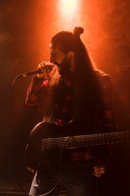 Ragazzo di chitarra con i capelli lunghi che canta