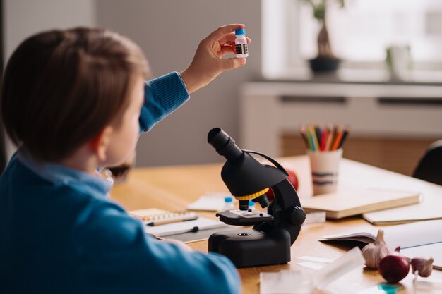 Ragazzo di prima elementare che studia a casa, fa esperimenti