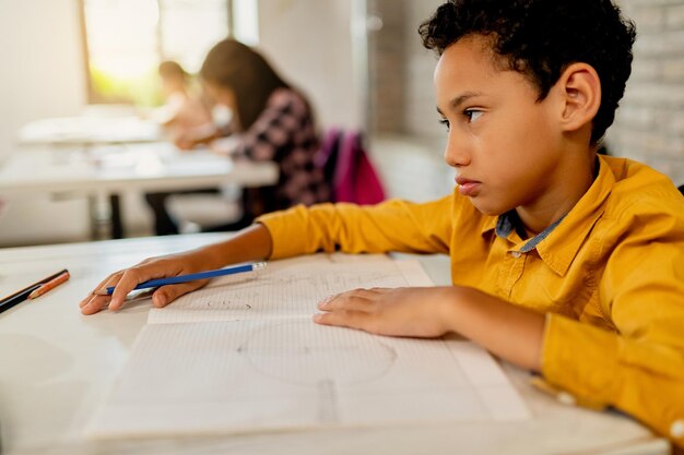 Ragazzo di scuola afroamericano dispiaciuto che impara in classe