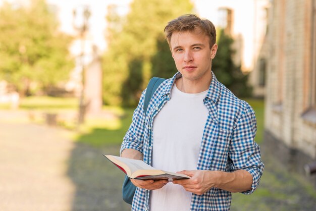 Ragazzo di scuola con il libro nel parco