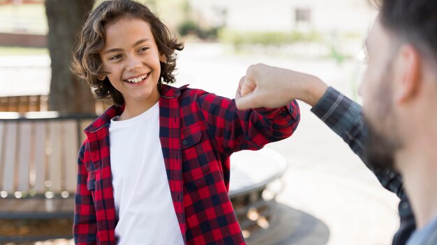 Ragazzo di smiley che bussa a pugno con suo padre mentre all'aperto