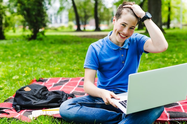 Ragazzo di smiley con il computer portatile nella natura