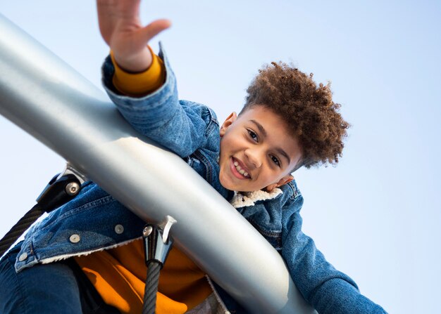 Ragazzo di smiley di angolo basso divertirsi al parco giochi