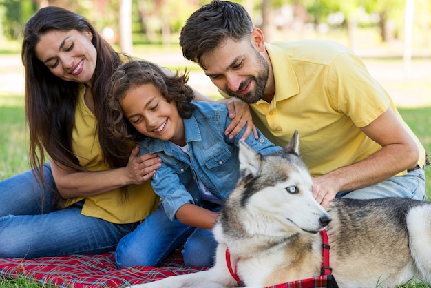 Ragazzo di smiley in posa al parco con cane e genitori