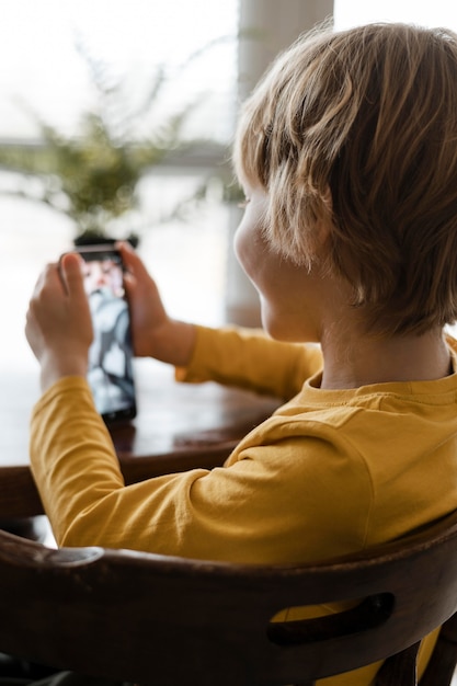 Ragazzo di smiley utilizzando smartphone a casa