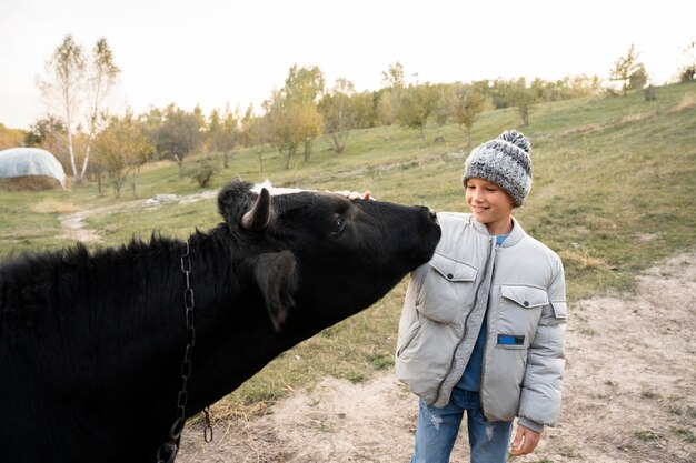 Ragazzo di tiro medio che accarezza una mucca