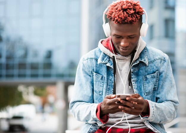 Ragazzo di tiro medio con smartphone e cuffie bianche