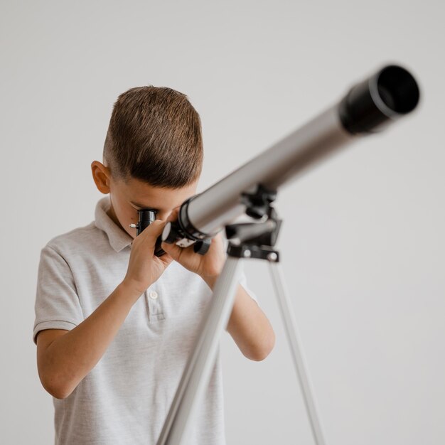 Ragazzo di vista frontale che utilizza un telescopio in classe