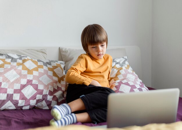 Ragazzo di vista frontale seduto a letto e apprendimento