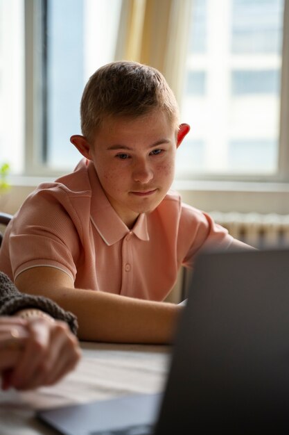 Ragazzo di vista laterale che esamina il computer portatile