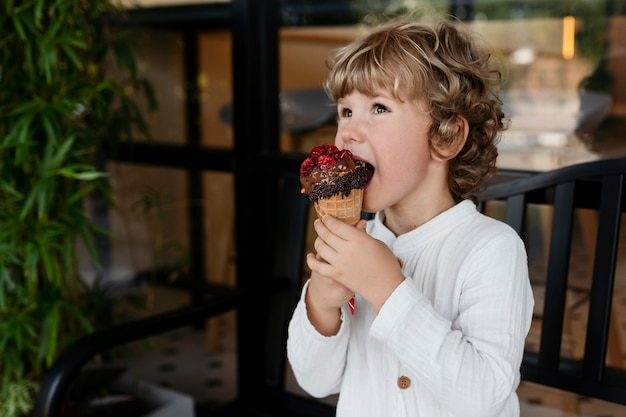 Ragazzo di vista laterale che lecca il cono gelato