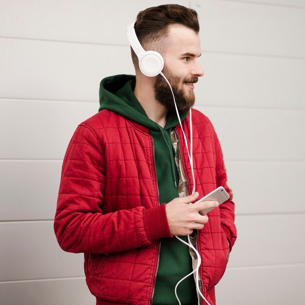 Ragazzo di vista laterale con barba e smartphone