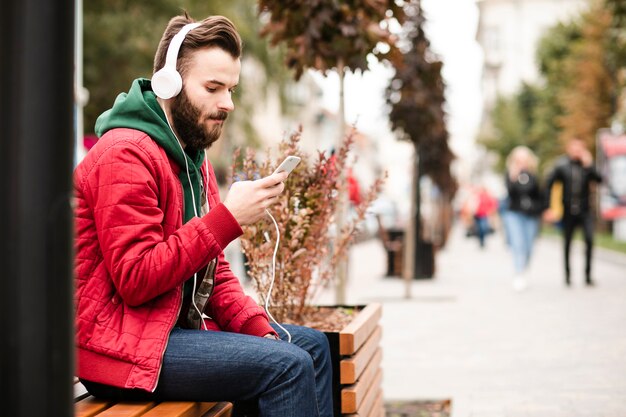 Ragazzo di vista laterale con cuffie e smartphone