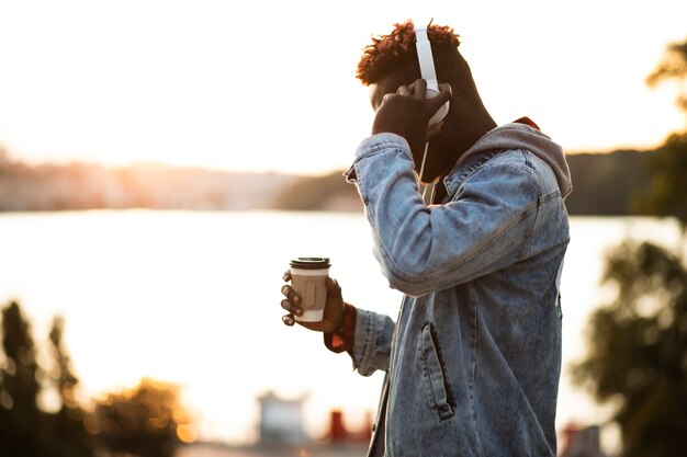 Ragazzo di vista laterale con cuffie e tazza di caffè