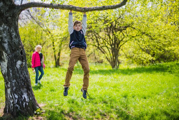 Ragazzo divertente che gioca su un ramo di albero