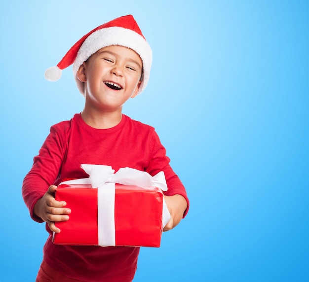 ragazzo divertente in possesso di un regalo rosso con sfondo blu