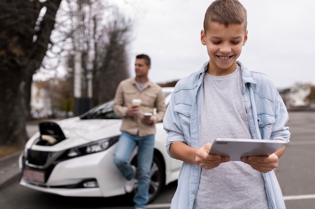 Ragazzo e papà vicino a un'auto elettrica