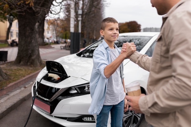 Ragazzo e papà vicino a un'auto elettrica