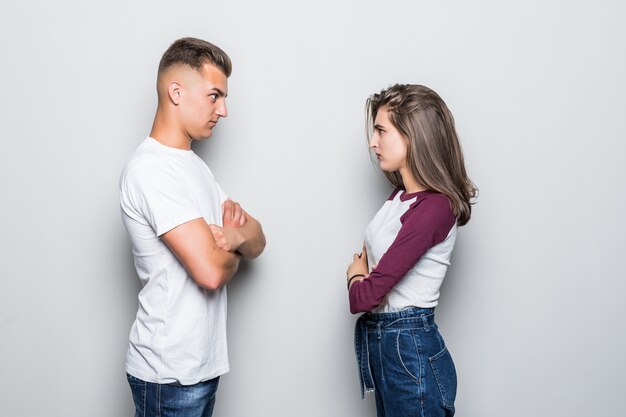 Ragazzo e ragazza belli abbastanza giovani delle coppie che sembrano arrabbiati l'uno sull'altro isolato su bianco