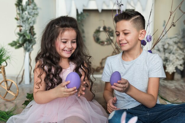 Ragazzo e ragazza che si siedono con le uova di Pasqua