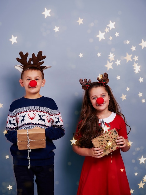 Ragazzo e ragazza con il contenitore di regalo della tenuta del corno della renna