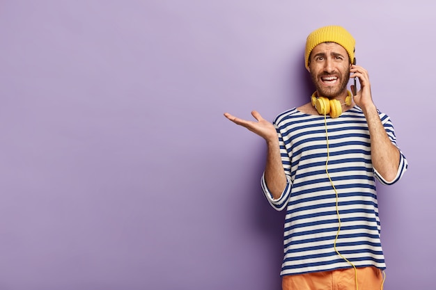 Ragazzo elegante perplesso in posa con il suo telefono