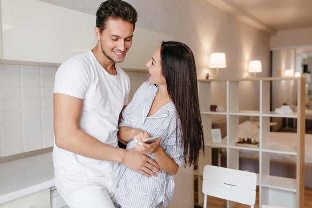 Ragazzo europeo dai capelli corti che tocca delicatamente l'affascinante moglie in pigiama blu