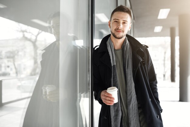 Ragazzo in abiti primaverili freschi rilassanti bevendo caffè fuori