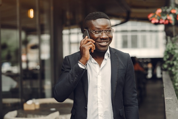 Ragazzo in abito nero. Maschio con un telefono cellulare. Uomo d'affari in ufficio.